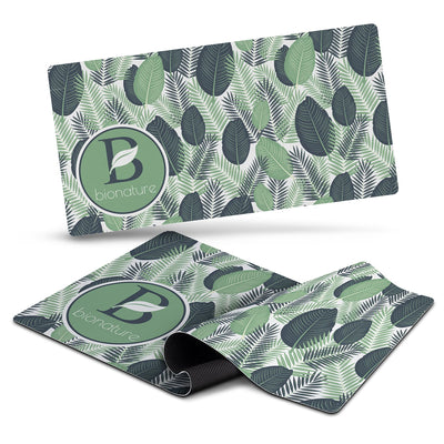 Desk Mat - A desk mat featuring a leafy green design with various shades of green and a circular logo.