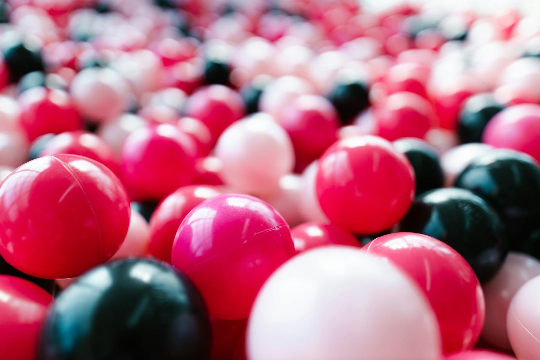 A lively close-up of red, pink, and black toy balls, perfect for backgrounds or playful themes.