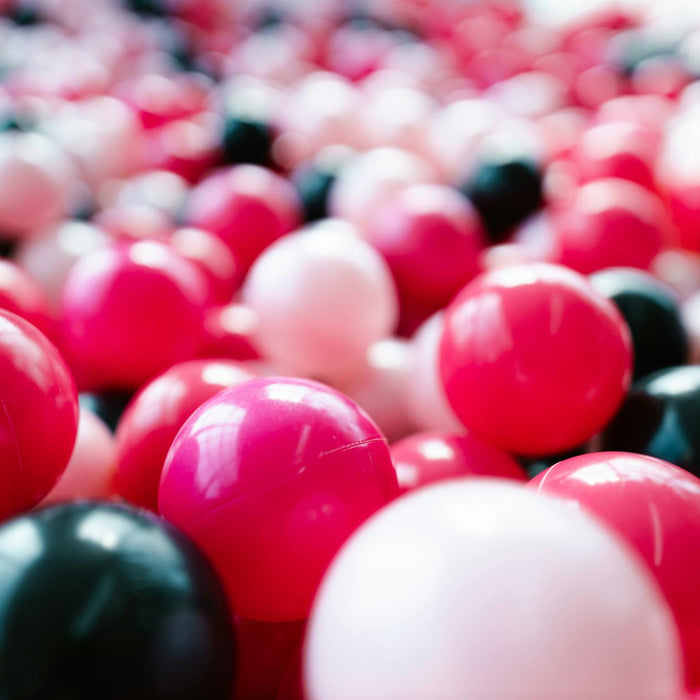 A lively close-up of red, pink, and black toy balls, perfect for backgrounds or playful themes.
