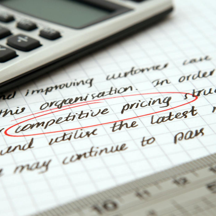Focused image of handwritten business notes with calculator emphasizing pricing strategy.