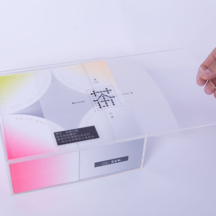 Sleek packaging design with a hand opening a transparent lid, showcasing elegant typography.
