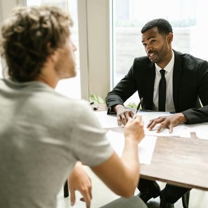 Two men having a discussion over documents in a modern office setting.