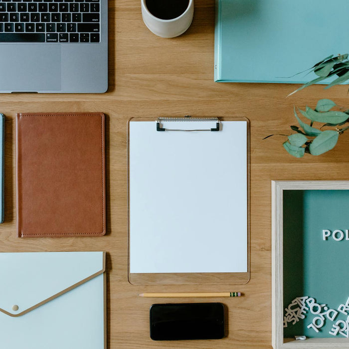 Stylish office supplies arranged neatly on a desk, including a laptop, clipboard, and notebooks.