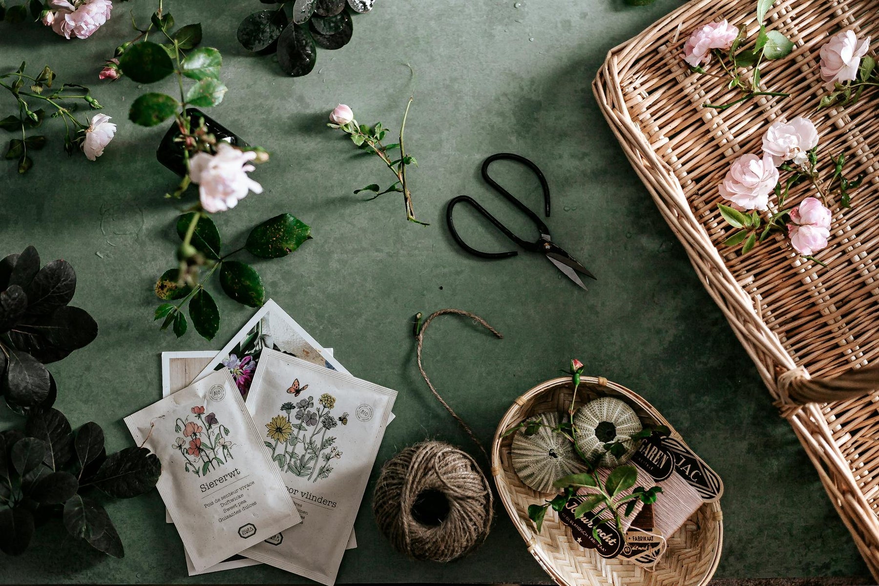 A beautiful flat lay of pink flowers, gardening tools, and baskets on a green surface, perfect for nature lovers.