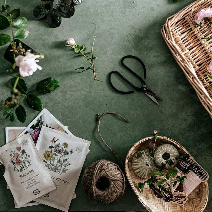 A beautiful flat lay of pink flowers, gardening tools, and baskets on a green surface, perfect for nature lovers.