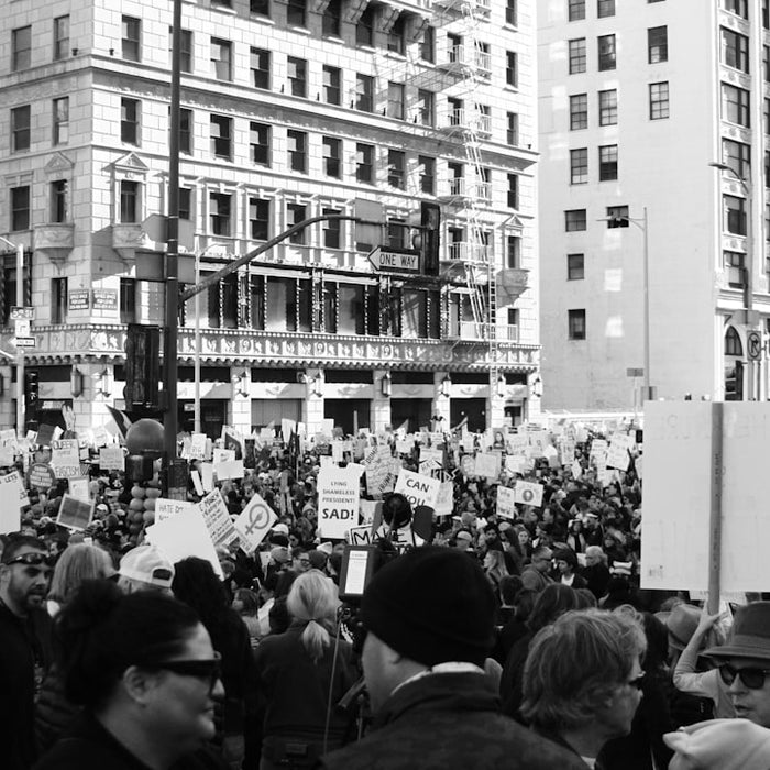 grayscale photography of people protesting in front of concrete building