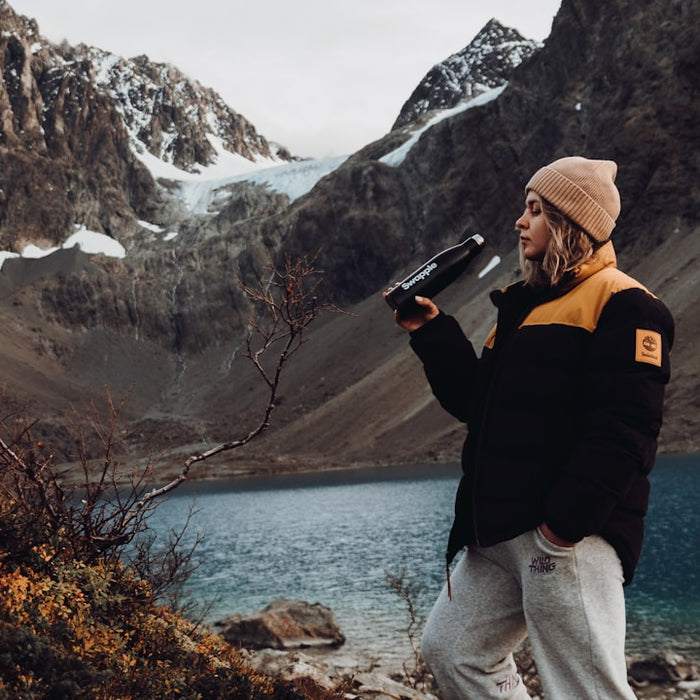 a man standing on top of a mountain next to a lake