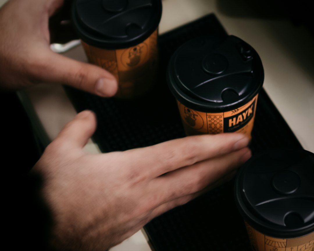 a person holding two cups of coffee on top of a table