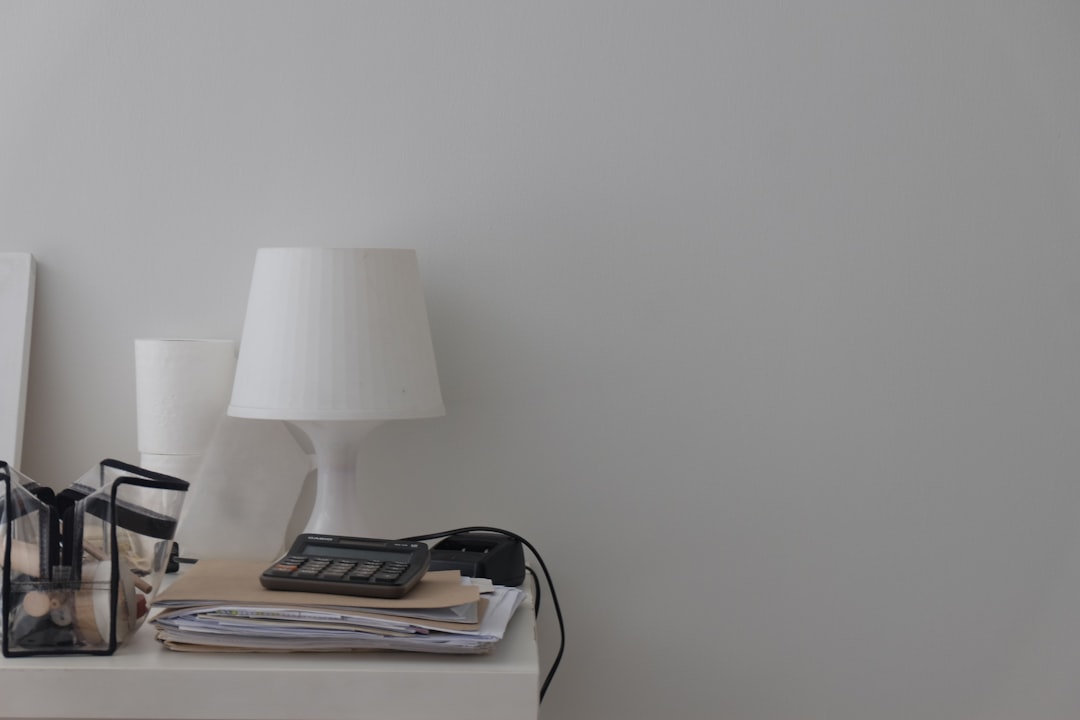 a white table topped with a lamp and a phone