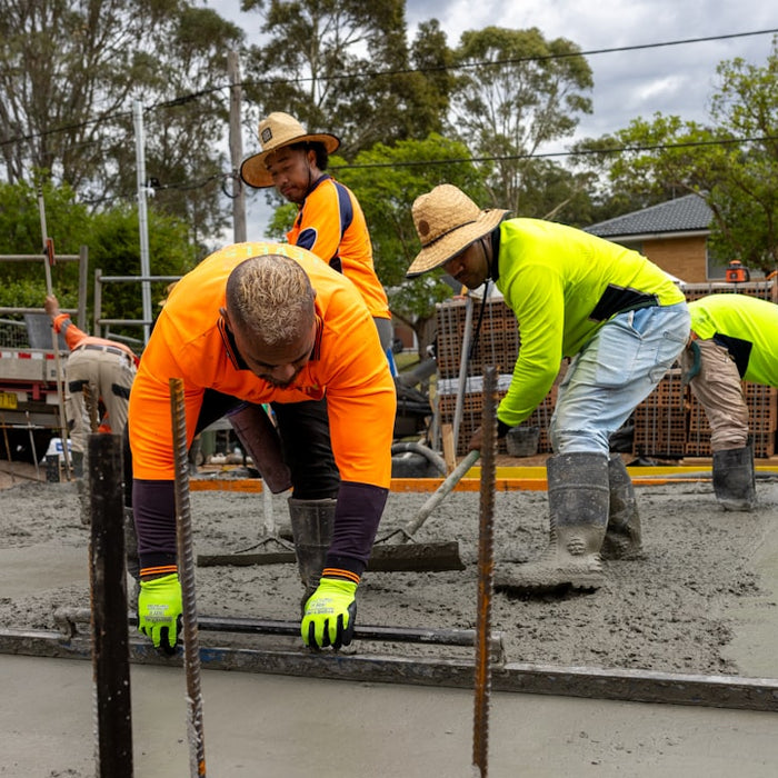 Construction workers pouring and leveling concrete.