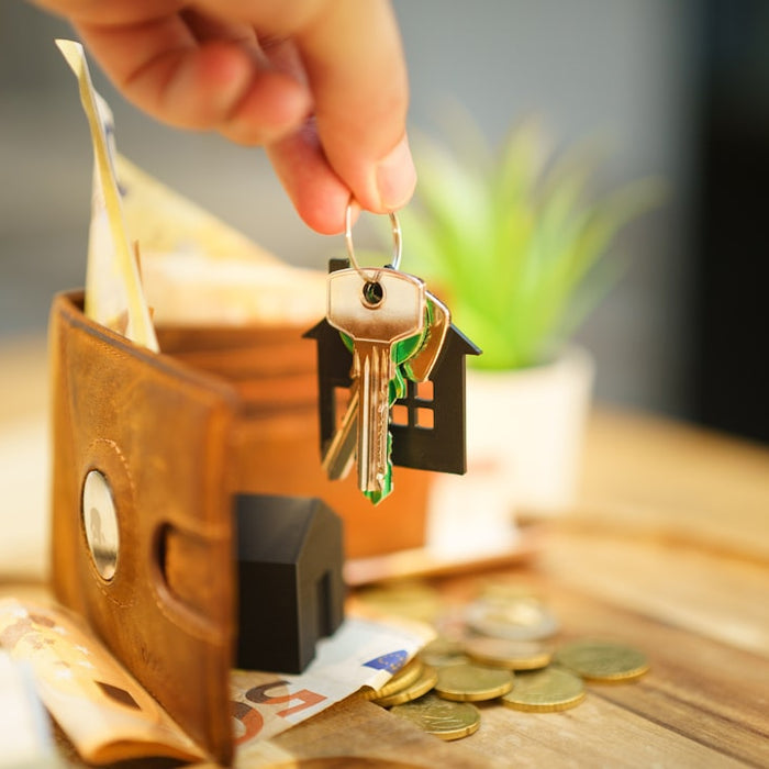 Hand holding keys with house charm and wallet