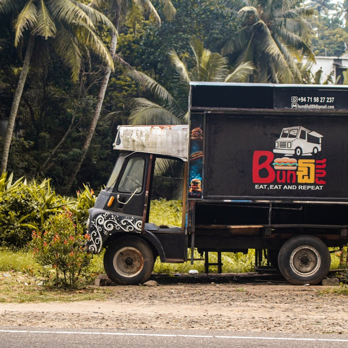 A food truck parked in front of some trees.