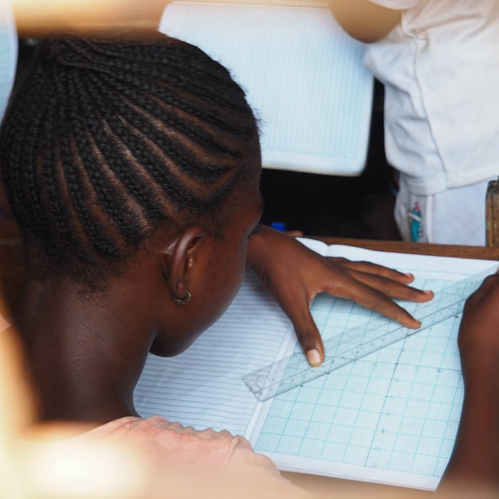 A student carefully draws lines with a ruler.