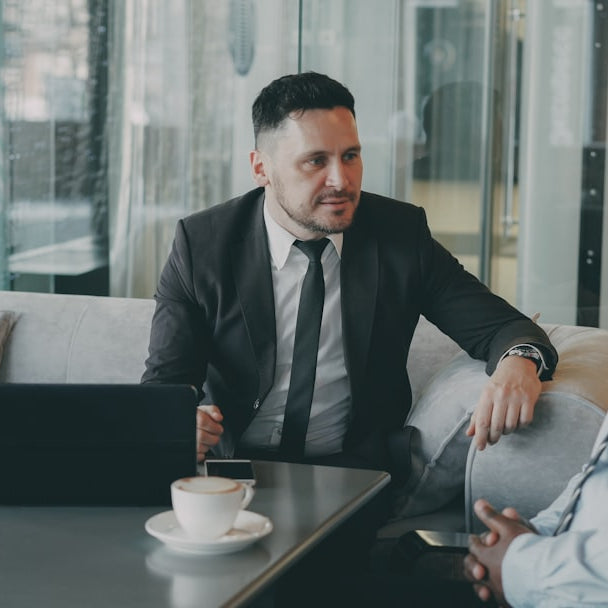 Two businessmen talking at a table with laptop.