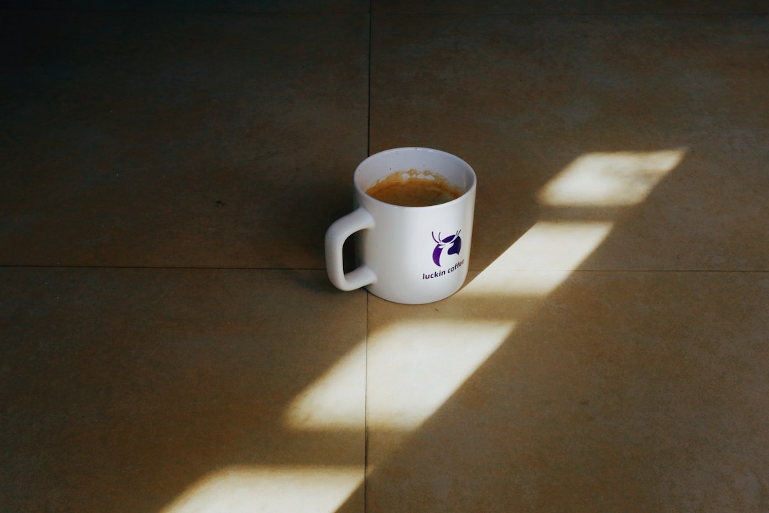 A white mug filled with coffee sits on a floor