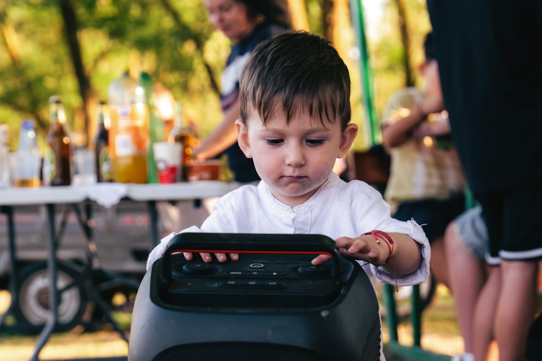 A child touching the controls of a portable speaker outdoors