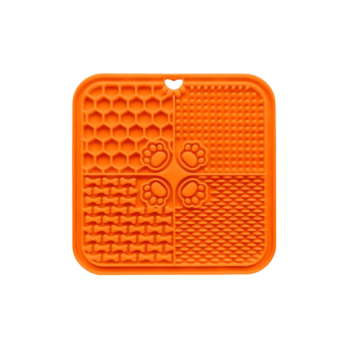 4-Section Dog Enrichment Lick Mat - An orange, four-section silicone lick mat with various textures, including paw prints and bone shapes.