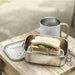 Seasons Titan Recycled Stainless Steel Lunch Box - A stainless steel lunch box with a sandwich inside, placed beside a drink bottle on a wooden surface.