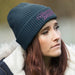 Galway Waffle Beanie - A grey waffle beanie with a branded logo, worn by a person with long hair and a thoughtful expression.