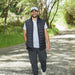 TRENDSWEAR Carter Men's Polo - A man wearing a grey polo shirt and a black vest walks along a gravel path surrounded by greenery.