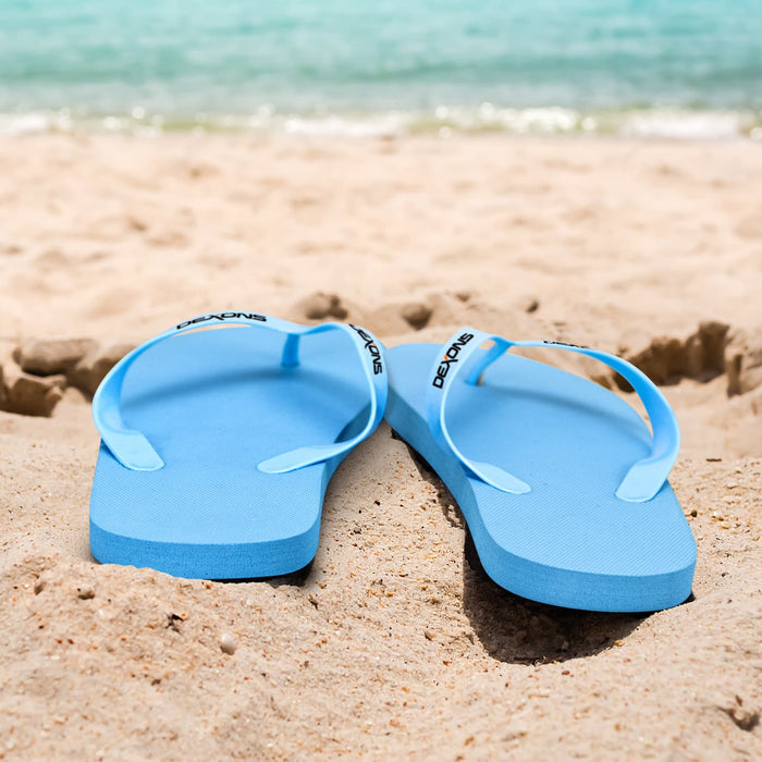 Tidal Flip Flops - Blue flip flops resting on sandy beach with calm waters in the background. Features a logo on the strap.