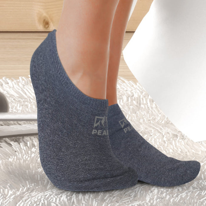 June Ankle Socks - Ankle socks in dark grey, featuring a logo, displayed on a person's feet on a textured surface.