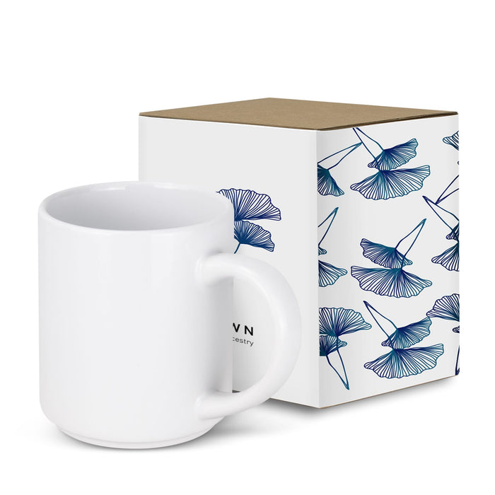 Arista Stackable Coffee Mug - A stackable white coffee mug next to a decorative box featuring blue floral designs. The box has a logo.