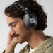 Skullcandy Hesh 360 Headphones - A pair of black Skullcandy Hesh 360 headphones worn by a man with curly hair, engaging with the headphones.
