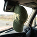 Vintage Washed Cap - A green vintage washed cap hanging from the mirror inside a vehicle, with a logo on the front.