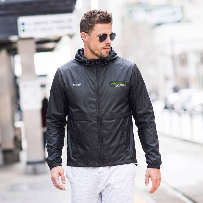 Swiss Peak Urban Unisex Windbreaker - A man wearing a black windbreaker with a hood, paired with sunglasses and light-coloured trousers. The jacket has a logo.