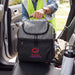 Trades Lunch Cooler Bag - A grey cooler bag with a logo, placed on the seat of a vehicle, alongside a drink bottle.