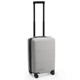Kadi Carry-On Suitcase - Leisure - A grey carry-on suitcase with four wheels and a retractable handle, featuring branding on the side.