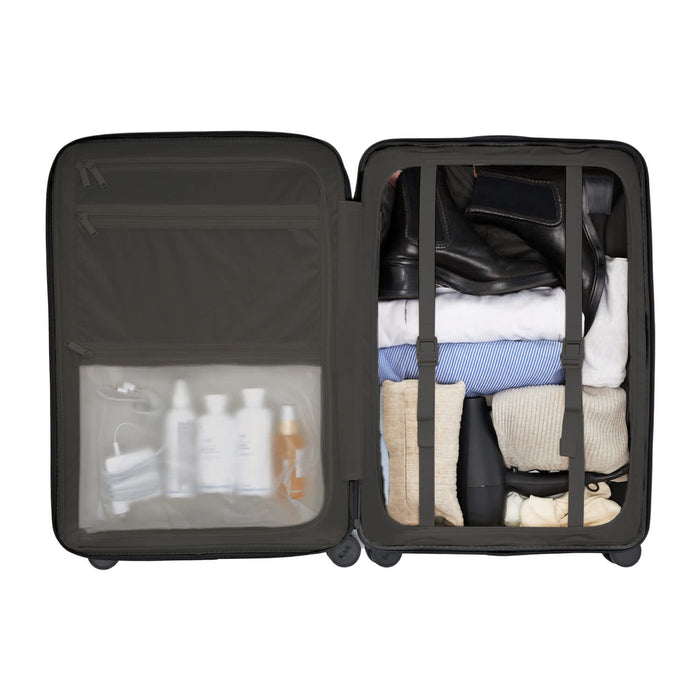 Kadi Check-In Suitcase - Medium - A medium black suitcase filled with neatly arranged clothes and toiletries, featuring a transparent compartment.