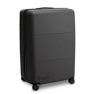 Kadi Check-In Suitcase - Large - A large black suitcase with a smooth exterior and wheels, featuring a brand logo on the side.