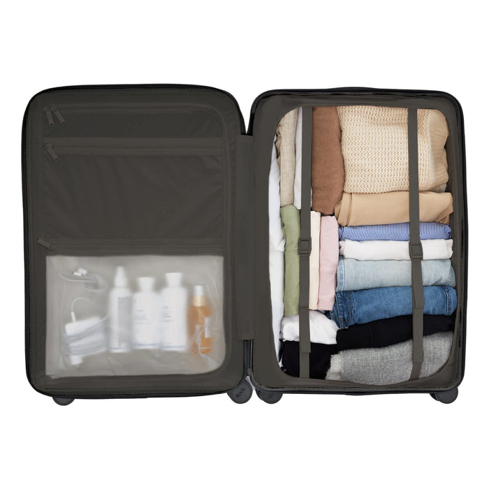 Kadi Check-In Suitcase - Large - A large dark grey suitcase with packed clothes and a clear pocket containing toiletries and a mask.