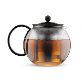 Bodum Assam Tea Press - A tea press in a round, glass design with a black lid and handle, filled with brewed tea. It features a built-in infuser.
