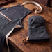 Keepsake Canvas Apron & Oven Mit Set - A dark grey canvas apron with light straps and a matching oven mitt, set against a wooden table.
