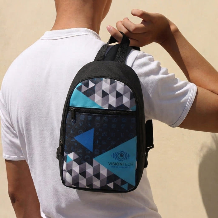 Callum Crossbody Bag - A crossbody bag featuring a geometric pattern in black, turquoise, and blue, held by a person. It has a logo.