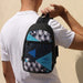 Callum Crossbody Bag - A crossbody bag featuring a geometric pattern in black, turquoise, and blue, held by a person. It has a logo.