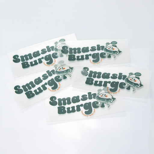 Prism Print - 100 x 50mm Sticker - A collection of green and white stickers featuring a playful logo and branding for "Smash Burger."
