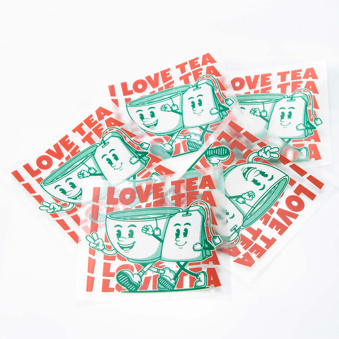 Prism Print - 100 x 100mm Sticker - A set of clear stickers featuring a smiling tea cup character and the phrase "I Love Tea" in red and green.