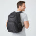 Fortress Laptop Backpack - A black laptop backpack with multiple compartments, worn on the back of a person smiling. It features a logo.