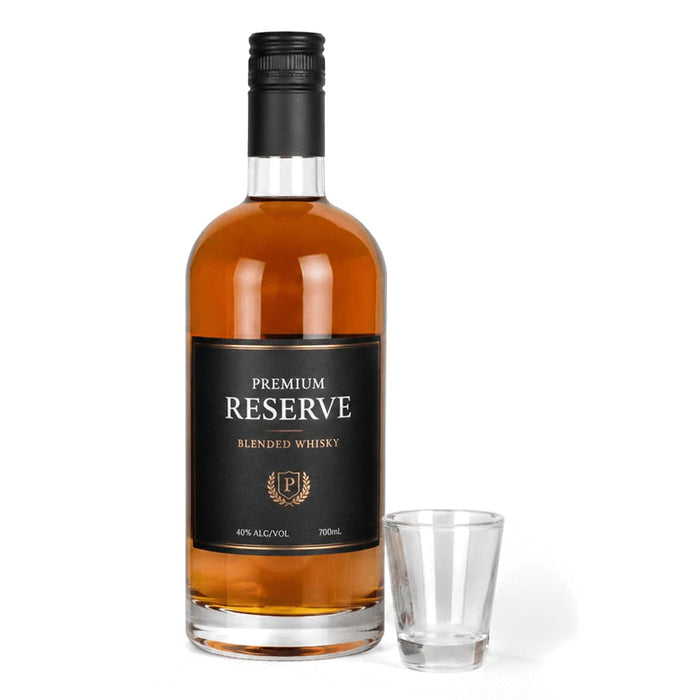 Shot Glass - A whisky bottle with a black label and a clear shot glass. The whisky is amber in colour.