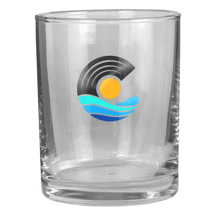 Rocks Glass - A clear rocks glass featuring a circular logo with waves and a sun design in blue and yellow.