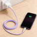 100W Fast Charging Cable - A purple 100W fast charging cable connected to a wall charger and an iPhone on a wooden surface.