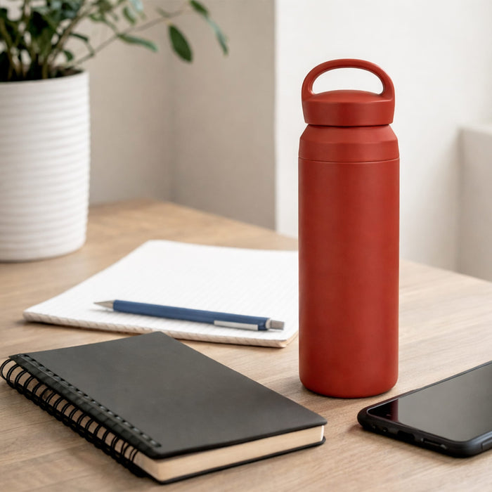 350ML/500ML Double Wall Stainless Steel Drink Bottle with Handle - A drink bottle in red, featuring a handle and double wall design, placed on a wooden desk with notebooks and a phone.