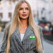 Custom Reusable Acrylic Name Badge - A woman with long blonde hair wears a grey checked blazer. She is outdoors in a blurred urban setting.