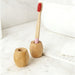Bamboo Toothbrush Stand - A bamboo toothbrush stand in natural wood tones, featuring two holders with a toothbrush placed in one.