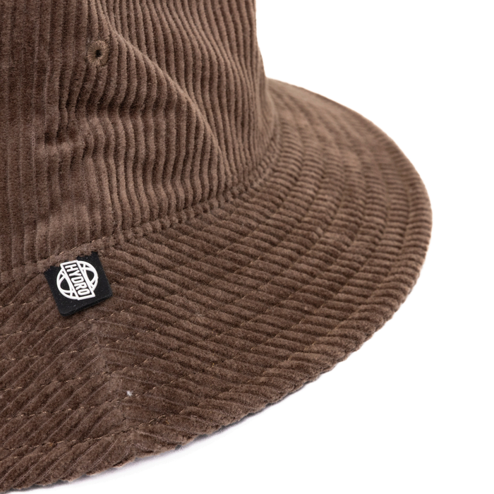 Atlanta Cord Bucket Hat - A brown corduroy bucket hat with a logo tag on the side. The texture is clearly visible in the image.