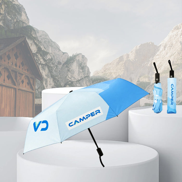 21'' Anti-rebound Folding Umbrella - A blue and white anti-rebound folding umbrella with a logo, displayed on a pedestal with a backdrop of mountains.